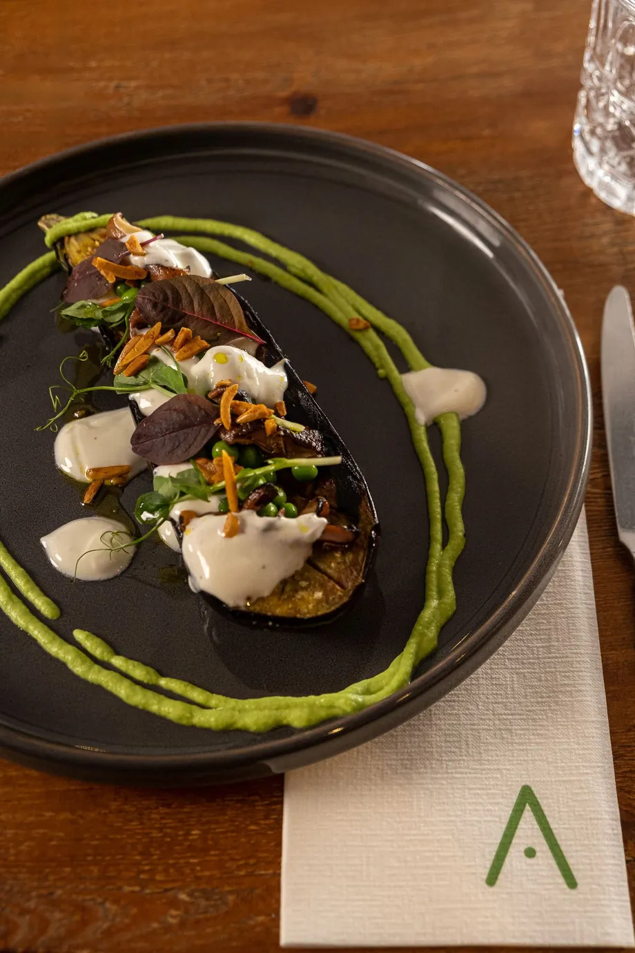 Beringela grelhada com Ras el Hanout, iogurte fumado, puré de ervilhas e amêndoa laminada